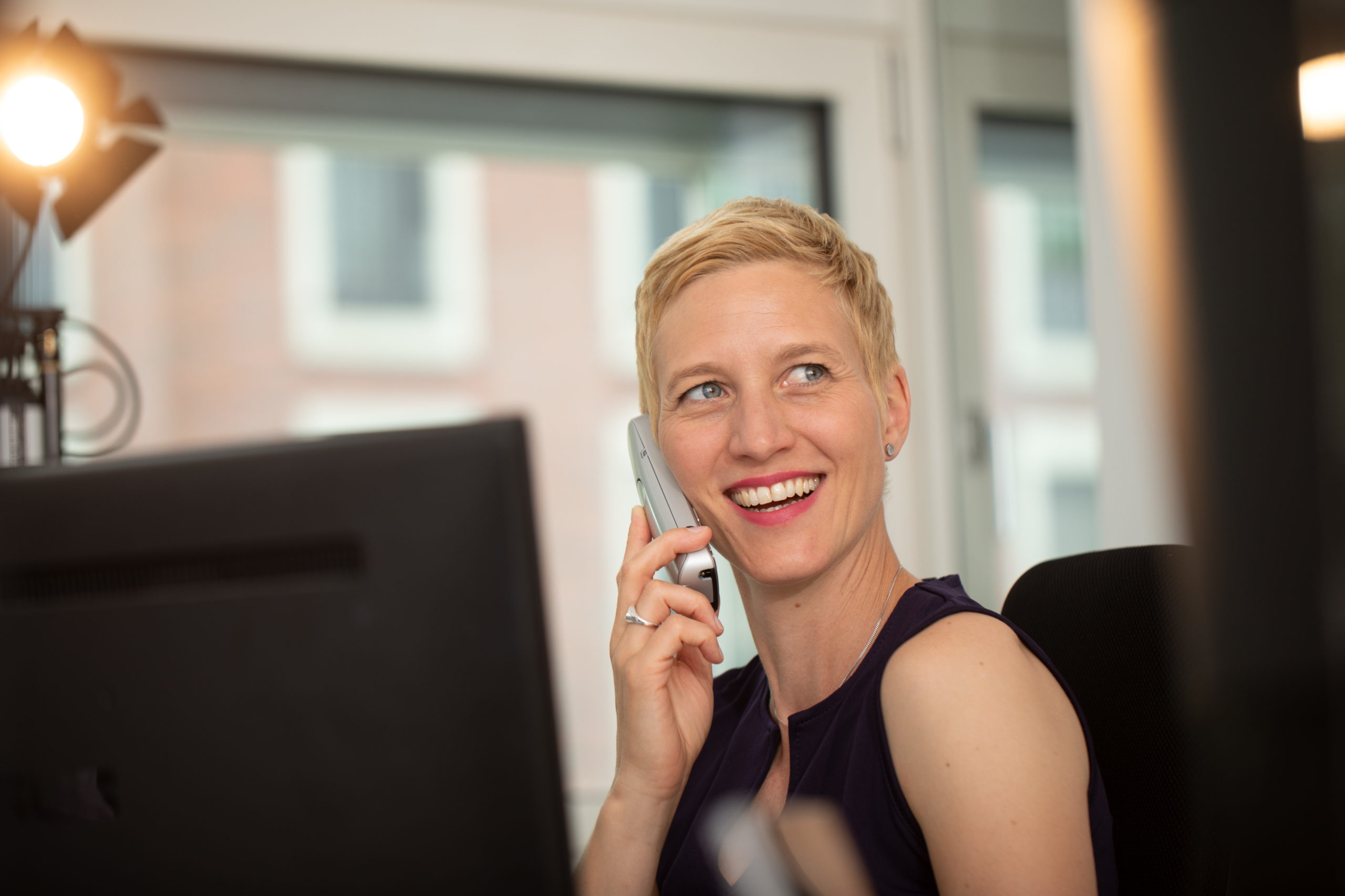 Susanne Schulz telefoniert im Büro und schaut dabei lächelnd und nachdenklich