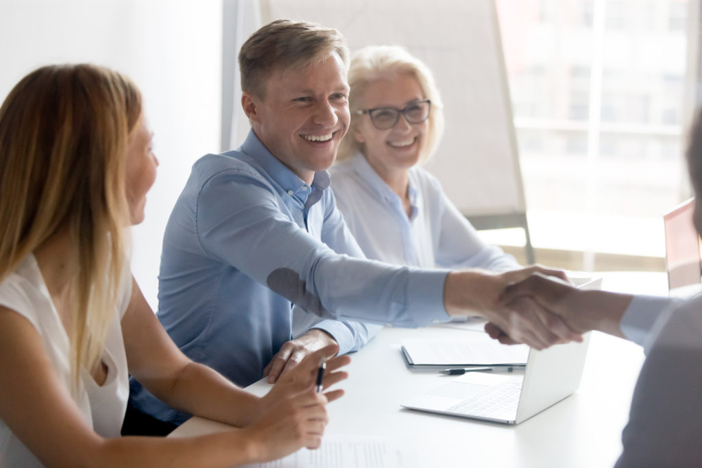 Fröhliche Menschen arbeiten zusammen und geben sich die Hand